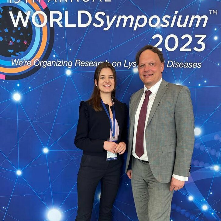 Mag.a Wiesinger und Prof. Lagler beim WORLD Symposium 2023 in Orlando/USA Mag. Wiesinger und Prof. Lagler stehen vor dem offiziellen Plakat des WORLD Symposiums 2023